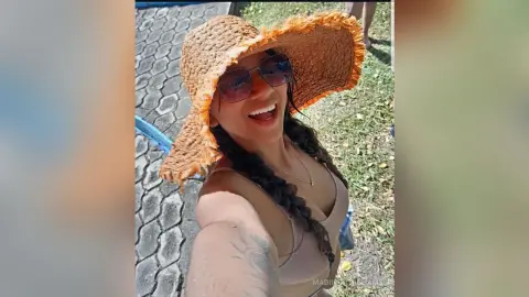 MadiisonWilliams smiles wearing a large straw sun hat and sunglasses, showing her long dark braided hair and tan skin outdoors.