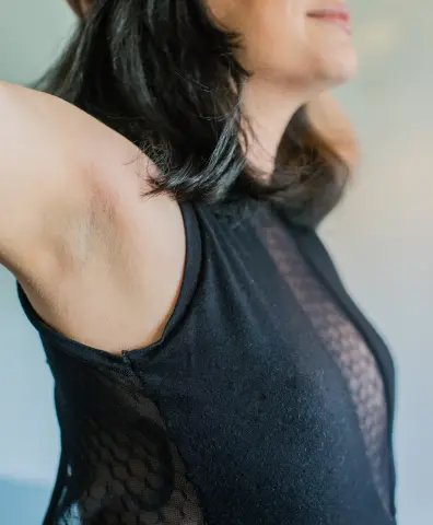 Close-up of a woman in a black mesh tank top against a neutral background with a soft, natural mood.