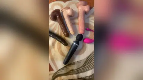 Assorted male pleasure toys and vibrators laid on a patterned fabric surface.