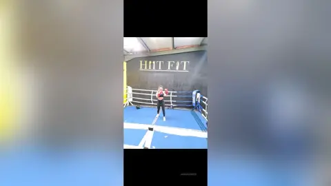 Fit woman in black workout gear training in a boxing ring at a HIIT FIT gym with a focused mood.