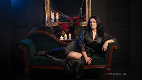 LaurenNewton — LaurenNewton sits on a green velvet sofa wearing a black silk robe with lace trim.