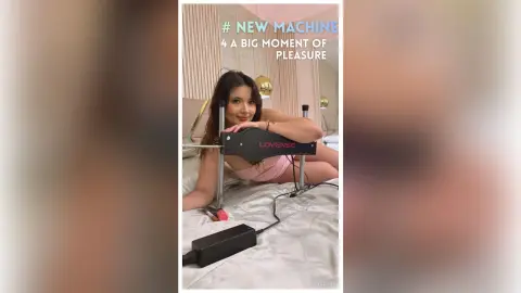 Young woman in pink loungewear relaxing on a white bed with a new black Lovense wellness device.