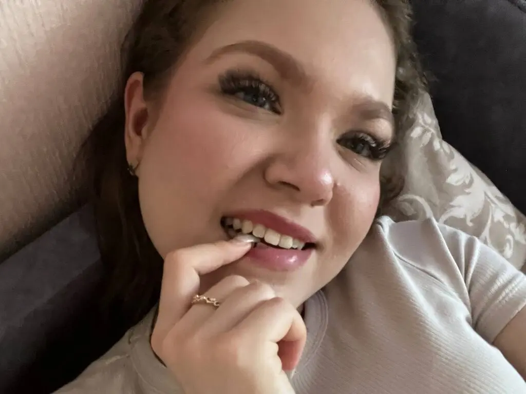 Smiling young woman in a white ribbed t-shirt relaxing on a patterned pillow at home.