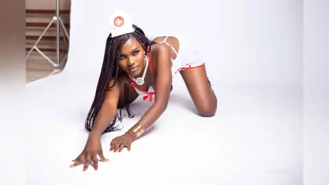 Beautiful Black woman in a white nurse outfit with braids posing confidently on a white studio background.