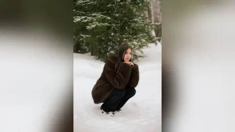 Elegant woman in a brown faux fur coat posing in a snowy winter forest setting.