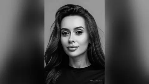 Close-up black and white portrait of a beautiful woman with long wavy hair looking serene and elegant.