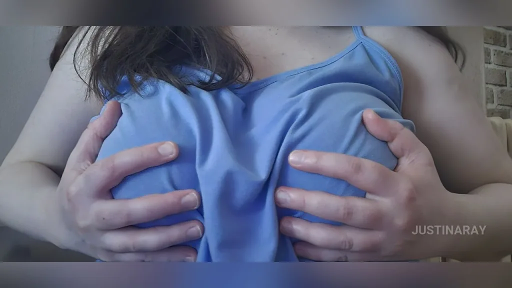 JustinaRay smiling at the camera with her long dark hair and hand under her chin.
