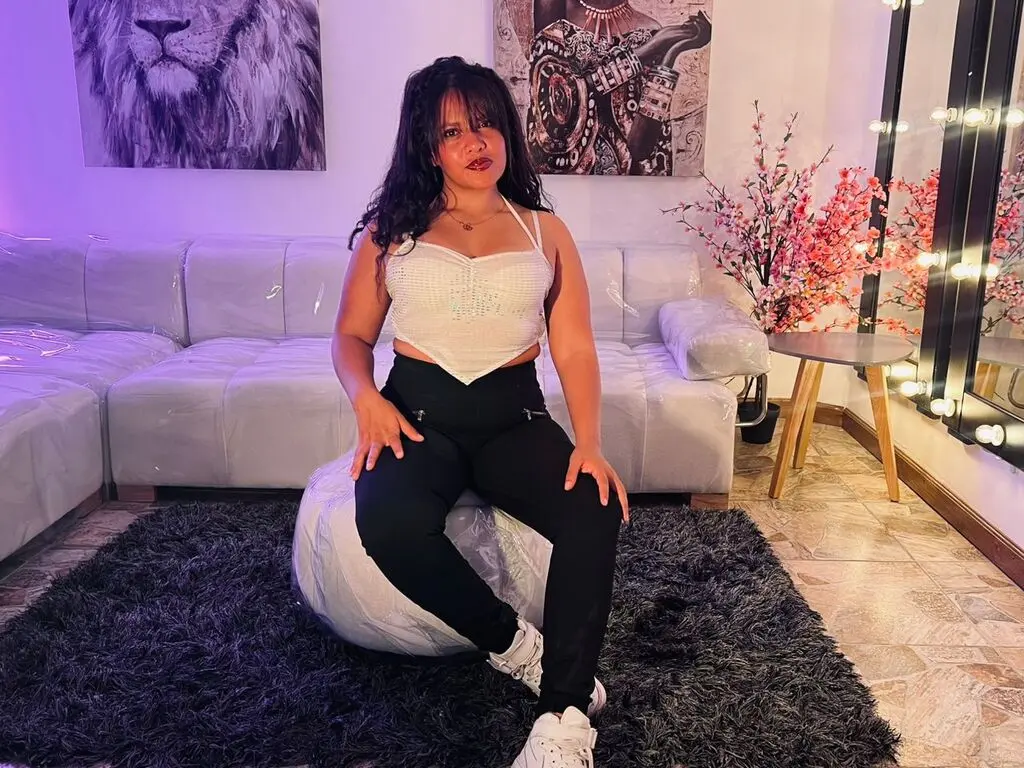 Woman in white crop top and black pants sitting on a white beanbag in a cozy, modern living room.