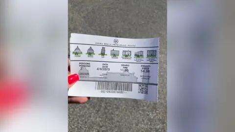 Close-up of a person holding a vintage Opera della Primaziale Pisana ticket for an event on April 4, 2023.