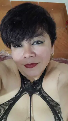 Woman with short dark hair wearing a black lace halter top in a warm indoor setting.