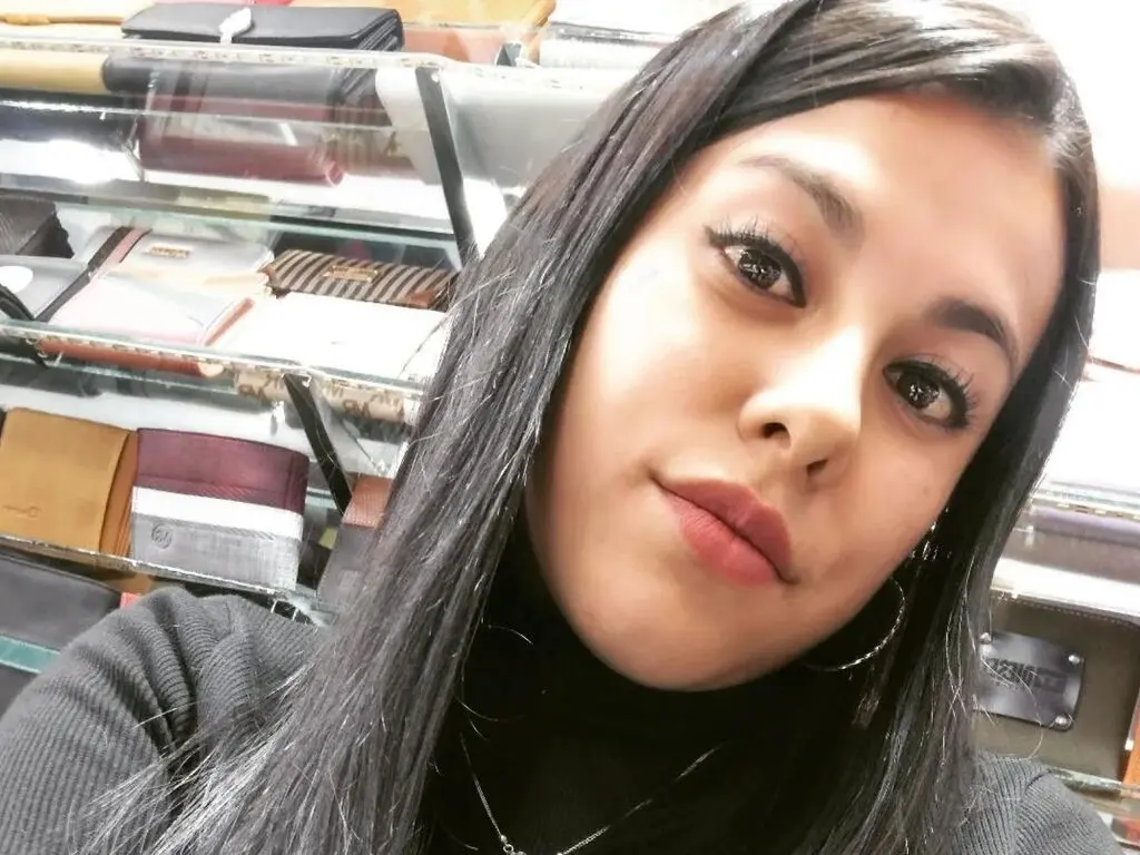 Young woman with long dark hair wearing a black turtleneck in a boutique setting.