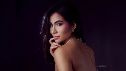 Elegant woman in a silver sequin dress posing with glamorous makeup against a dark moody background.