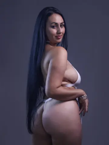 ValentinaJaramilloo poses naked in a white string bikini, showing her long black hair and bare back against a plain grey background.