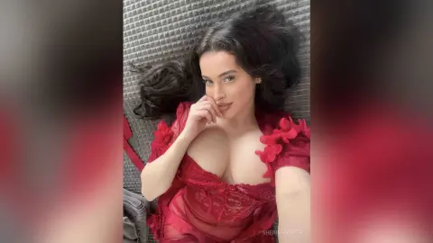 Beautiful woman in a red lace dress lying on a textured grey background with a romantic mood.