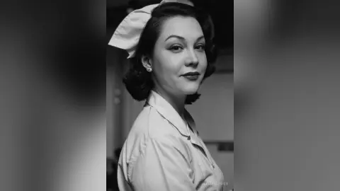 Elegant woman in vintage 1950s style blouse and hair bow posing with a classic retro aesthetic.