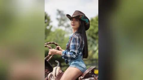 JessieLiu wears a brown cowboy hat and a blue plaid shirt while sitting on a horse outdoors.