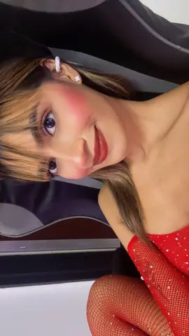 Smiling young woman in a red sparkly top and fishnet outfit posing for a close-up portrait.