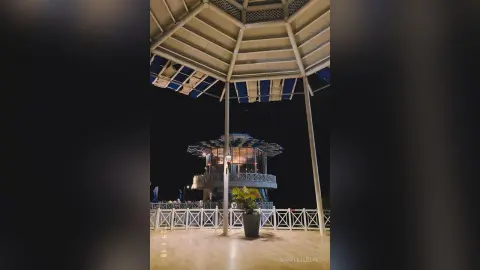 Modern illuminated gazebo structure under a dark night sky in a peaceful outdoor park setting.