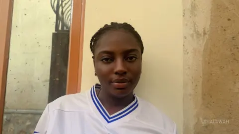 Shaluwah — Shaluwah wears a white jersey with blue trim and looks at the camera.