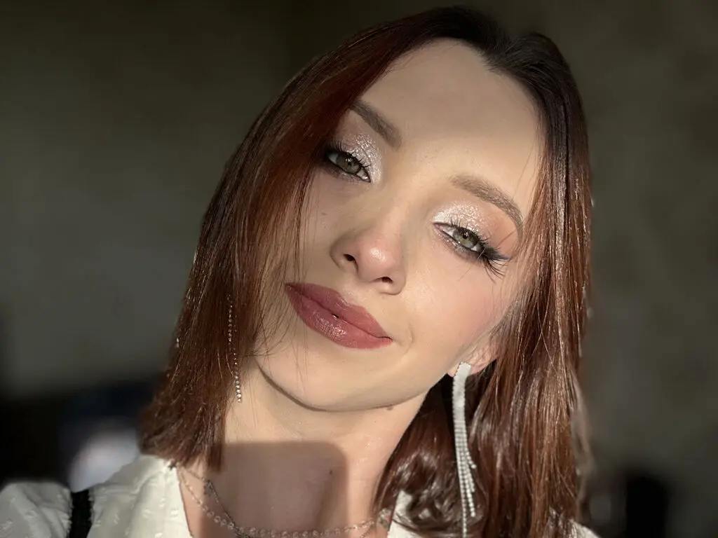 Young woman with glitter eyeshadow and silver earrings posing in soft natural lighting.