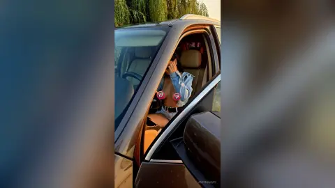 Young woman in a denim jacket sitting in a car during a golden hour sunset outdoors.