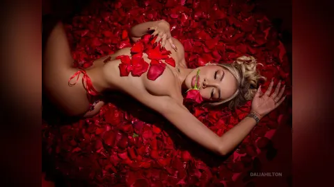 DaliaHilton — DaliaHilton lies naked on a bed of red rose petals with red flower petals scattered over her breasts.