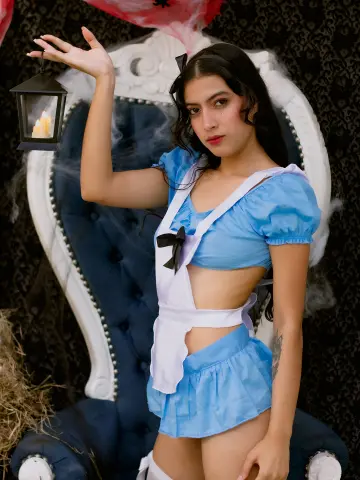 SusanaSanchez20 wears a light blue maid outfit with a white apron, holding a lit lantern while sitting in a large white chair.