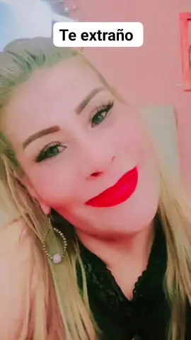 Smiling blonde woman with red lipstick and hoop earrings in a warm indoor setting.