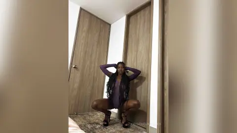 Confident woman in a purple long-sleeve bodysuit posing in a modern minimalist room.