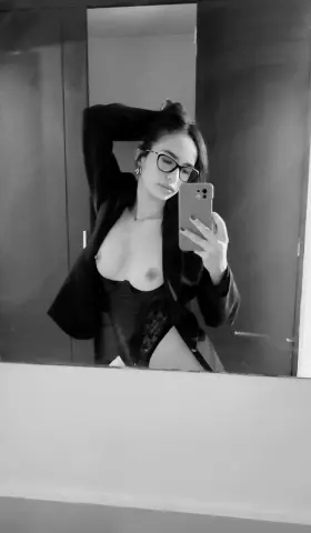 LIAMAXWELL poses for a mirror selfie, wearing a black open shirt that exposes her bare breasts.