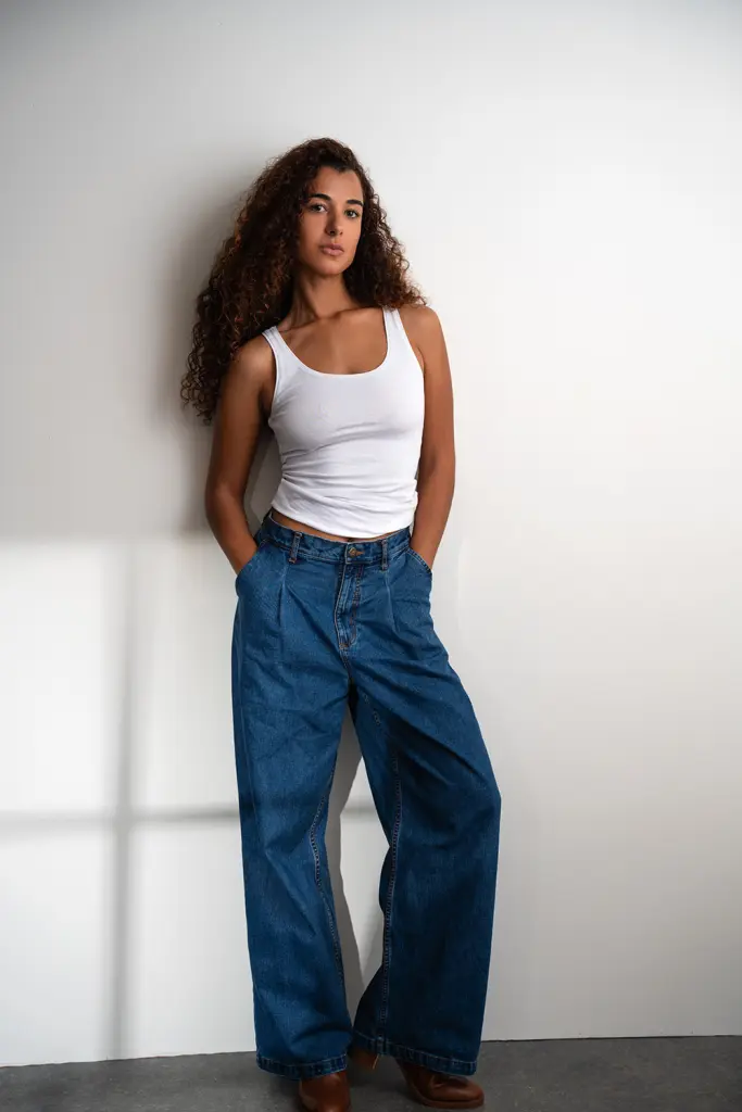 MissMilano_xo poses with her long, curly brown hair down, showing her bare shoulders and chest against a white background.