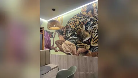 Modern dining area featuring a large leopard mural, warm pendant lighting, and neutral contemporary furniture.