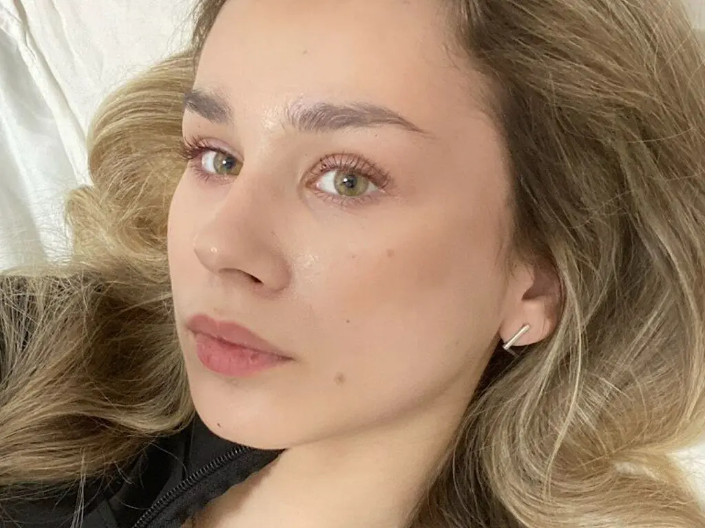 Close-up portrait of a young woman with blonde hair and natural makeup looking calmly at the camera.