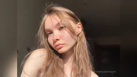 Young woman with long blonde hair posing in warm sunlight for a dreamy, sun-kissed portrait.