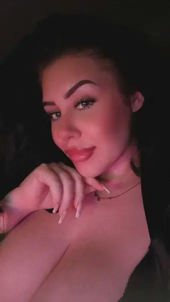 xAmberHeartx poses with her blonde hair down, showing off her cleavage in a low-cut brown top.