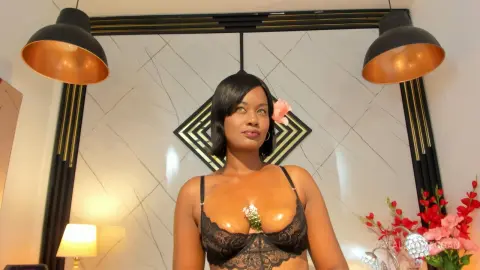 Smiling woman in black lace lingerie posing in a modern luxury room with warm lighting.