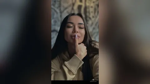 EmmyLee — EmmyLee winks and holds a finger to her lips while wearing a tan hoodie.