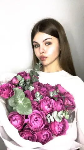 Young woman in a white t-shirt holding a large bouquet of pink roses against a white background.