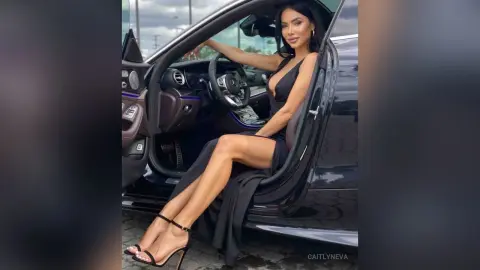 Elegant woman in a black evening gown sitting in a luxury car for a glamorous outdoor photoshoot.