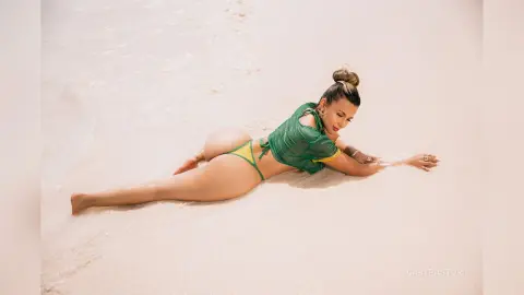 Woman in a green bikini relaxing on a sunny white sand beach in a peaceful summer mood.