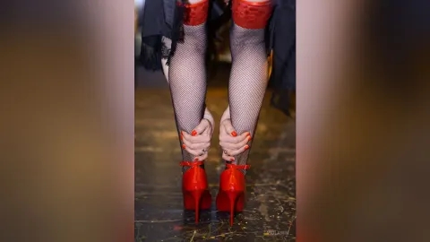 ViolaWin — ViolaWin wears red high heels and fishnet stockings while leaning forward.