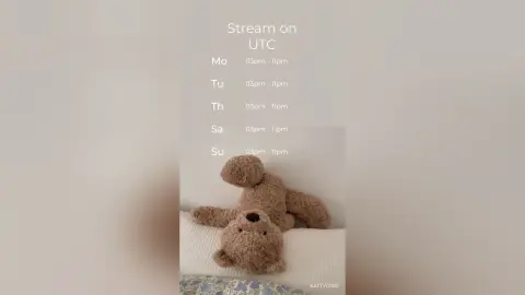 Cozy brown teddy bear sitting on a white bed in a soft, minimalist aesthetic room setting.
