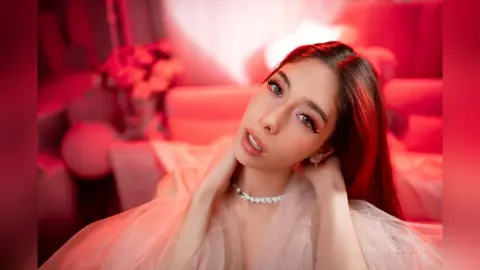 Young woman in a white tulle gown posing in a dreamy, soft pink romantic setting.
