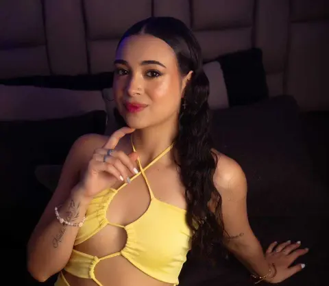 Smiling woman in a yellow halter neck top relaxing in a dimly lit room.