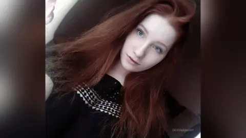 Portrait of a fair-skinned redhead woman in a black lace top with a dreamy, ethereal mood.