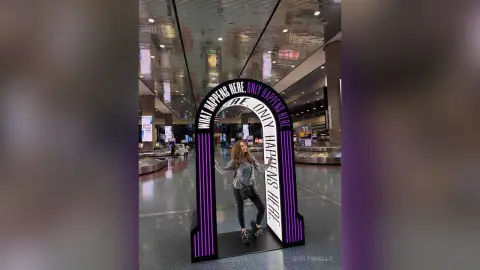 EvelynMills stands inside a large black and purple archway way in a bright, modern indoor hall or terminal.