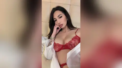Beautiful woman in red lace lingerie and a white robe relaxing in a bedroom setting.