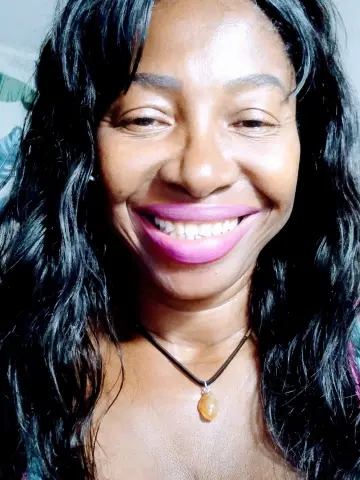 Ebonyhotxxx smiling for a close-up selfie with long wavy black hair and bright pink lipstick.