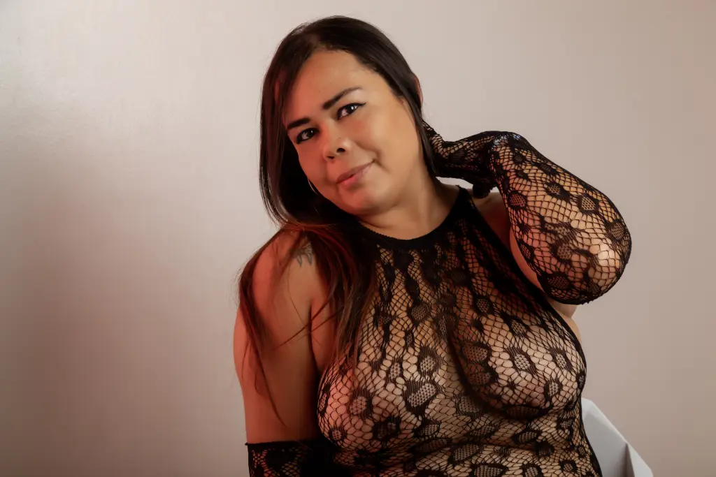 ChiiaraFiorre smiles while tilting her head, showing her dark hair and a small tattoo on her shoulder and wrist.