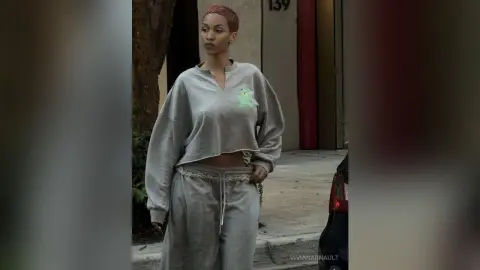 Stylish woman in a grey oversized sweatshirt and matching sweatpants standing on a city street.